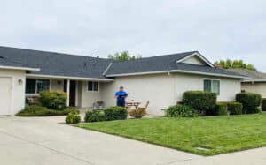 A well-maintained Sacramento home with a visible roof and a professional reviewing notes outside, illustrating how roof maintenance plans support long-term roof care and prevention.